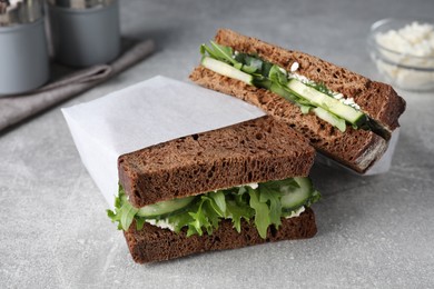 Photo of Tasty sandwiches with cream cheese, cucumber and greens on light grey table