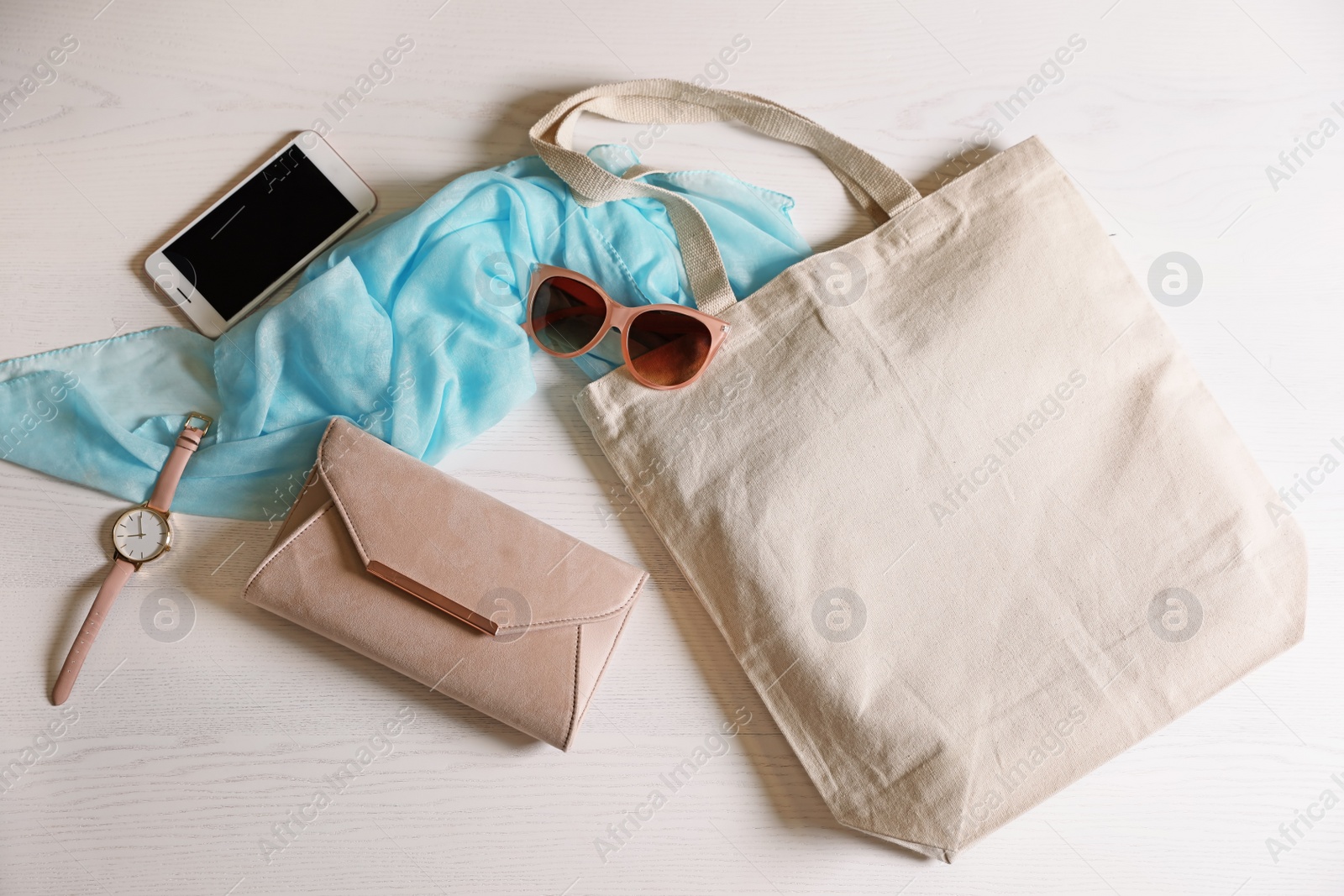 Photo of Flat lay composition with eco tote bag, smartphone and accessories on white wooden background. Space for design