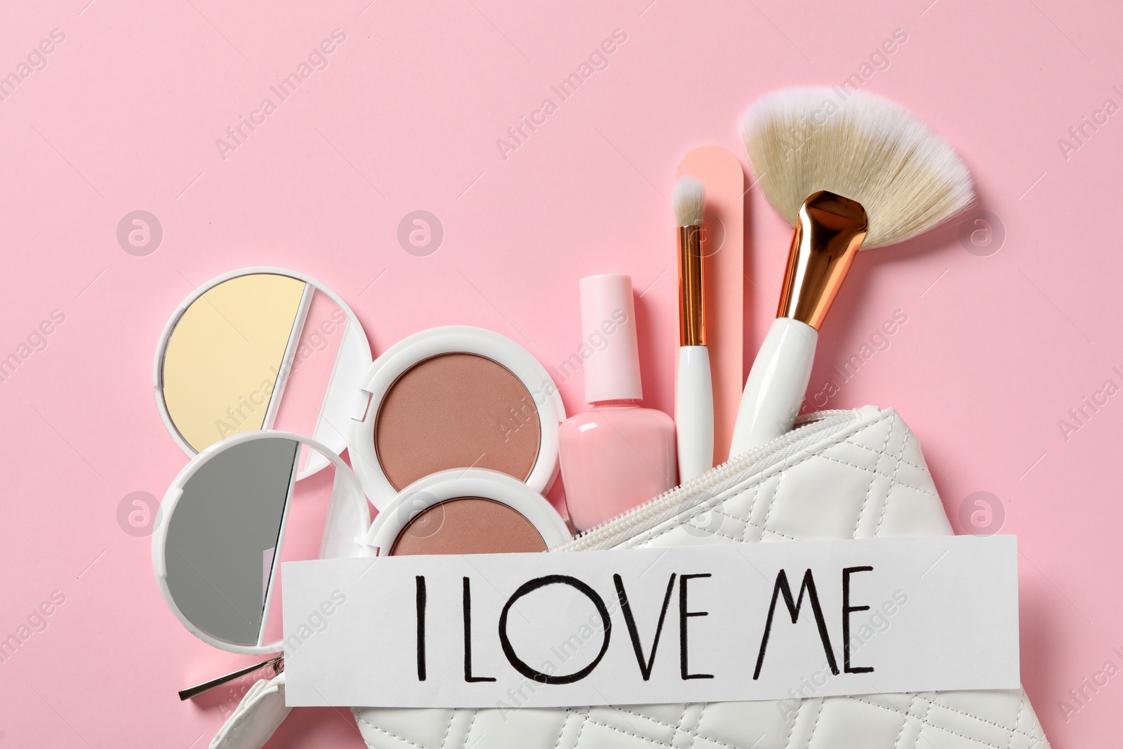 Photo of Paper with handwritten phrase I Love Me and makeup products on pink background, flat lay