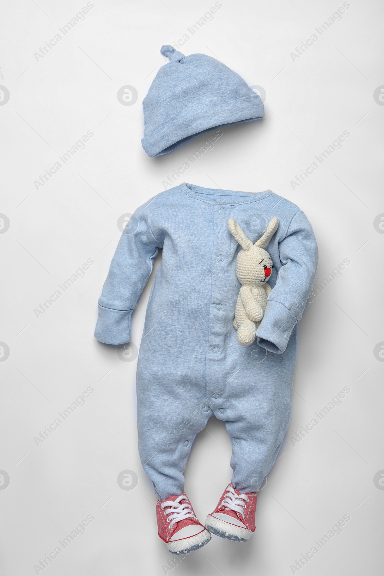 Photo of Child's clothes, booties and toy bunny on white wooden background, flat lay