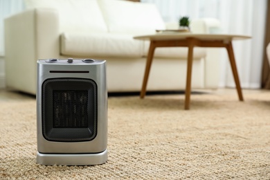 Photo of Modern electric fan heater on floor at home. Space for text