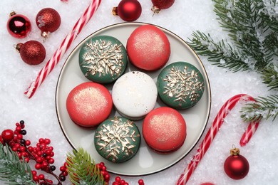 Beautifully decorated Christmas macarons, candy canes and festive decor on snow, flat lay