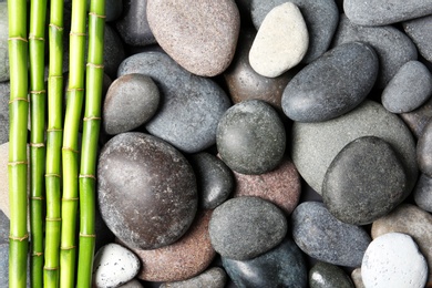 Photo of Composition with spa stones and bamboo branches as background, top view