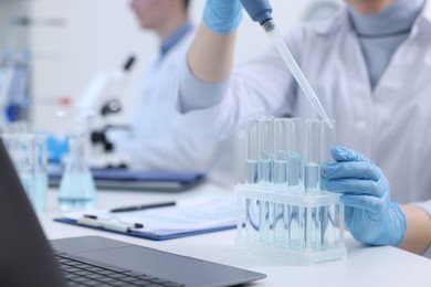 Photo of Scientist dripping sample into test tube in laboratory, closeup