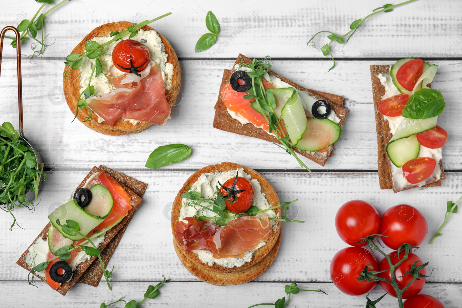 Photo of Tasty rusks and rye crispbreads with different toppings on white wooden table, flat lay