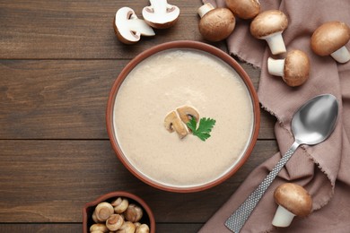 Photo of Delicious mushroom cream soup with parsley served on wooden table, flat lay. Space for text
