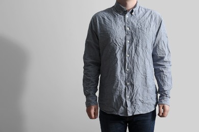 Photo of Man wearing creased shirt on light background, closeup. Space for text