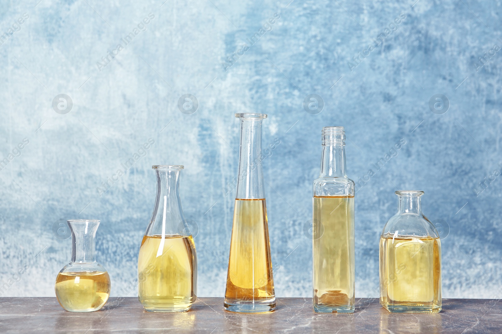 Photo of Row of different glass bottles with oil on color background