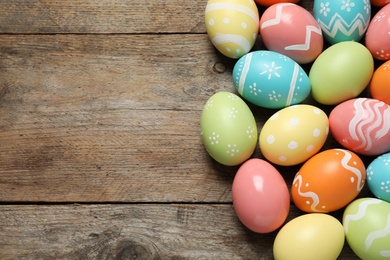 Photo of Many colorful painted Easter eggs on wooden background, top view. Space for text