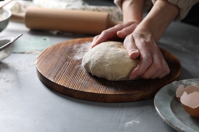 Photo of Woman kneading dough at grey table, closeup