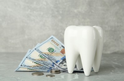Photo of Ceramic model of tooth and money on grey table. Expensive treatment