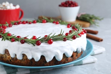 Photo of Traditional Christmas cake decorated with rosemary and cranberries on light grey marble table, closeup