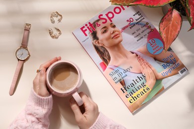 Photo of Woman with cup of coffee, magazine and accessories at table, top view