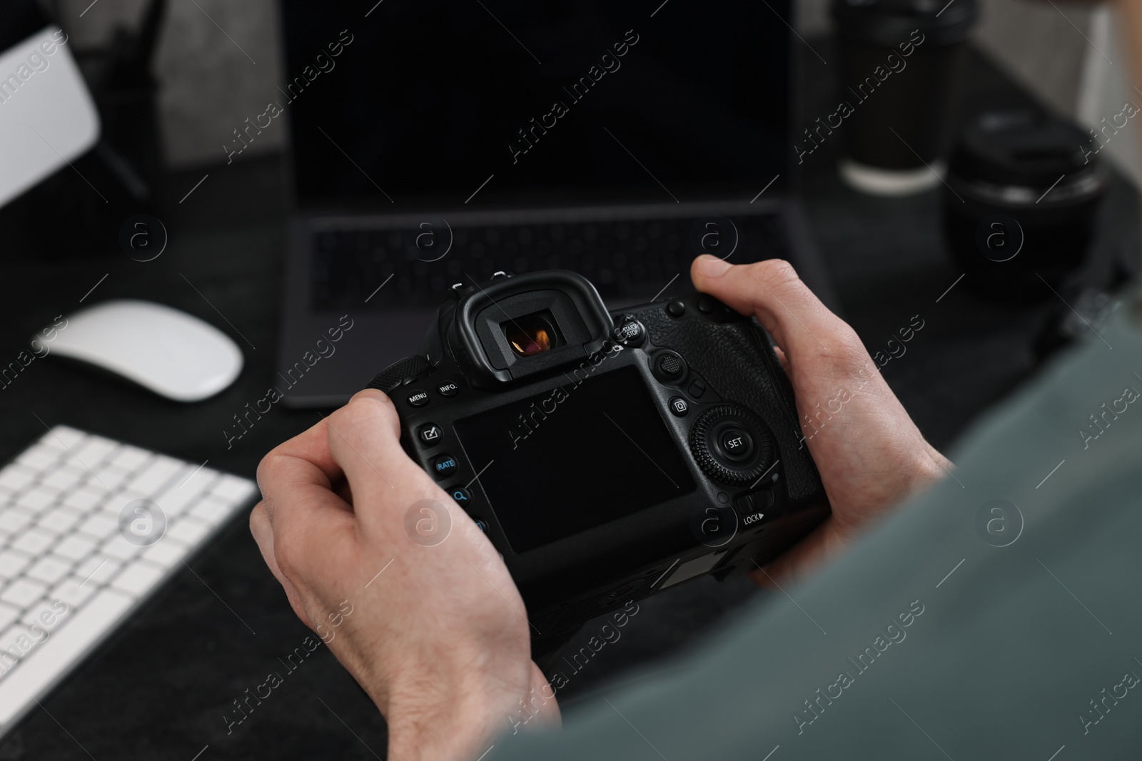 Photo of Photographer holding camera near dark table, closeup