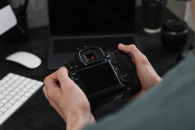 Photo of Photographer holding camera near dark table, closeup