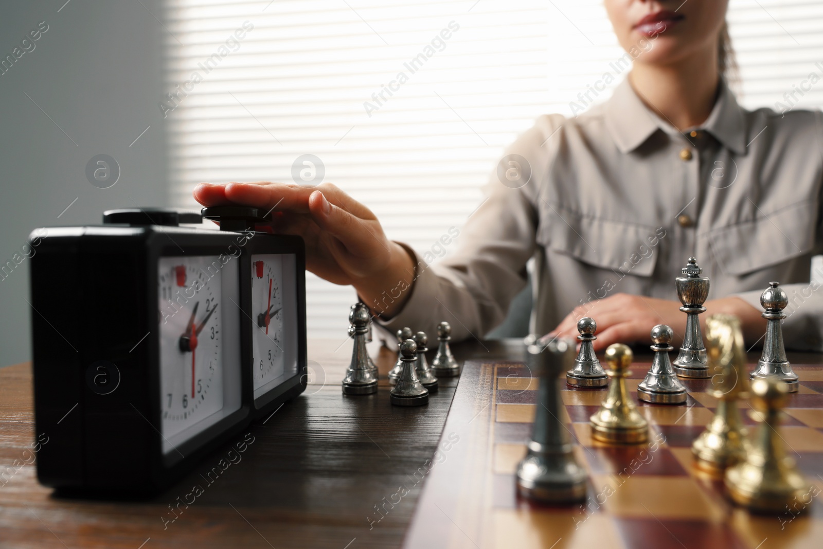 Photo of Woman turning on chess clock during tournament at table, closeup