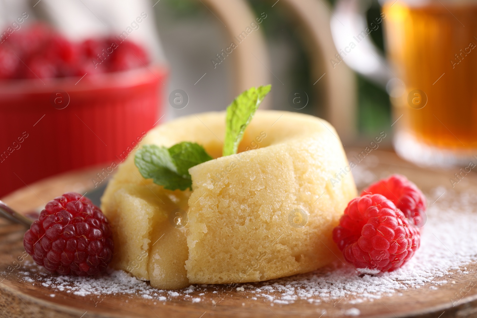 Photo of Tasty vanilla fondant with white chocolate and raspberries on wooden board, closeup