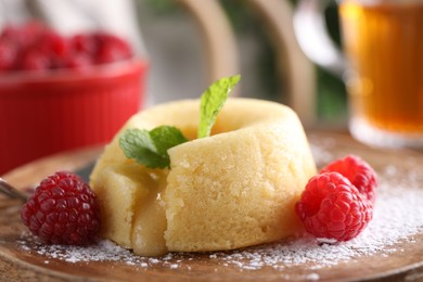 Tasty vanilla fondant with white chocolate and raspberries on wooden board, closeup