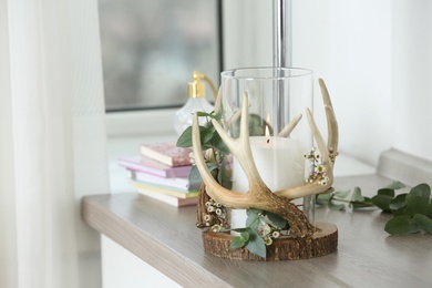 Photo of Burning candle in beautiful glass holder on wooden table indoors