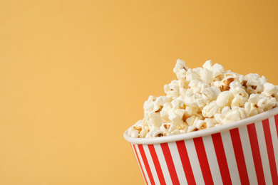 Photo of Delicious popcorn on yellow background, closeup. Space for text