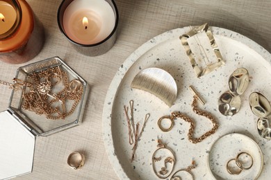 Photo of Stylish golden bijouterie and candles on wooden table, flat lay