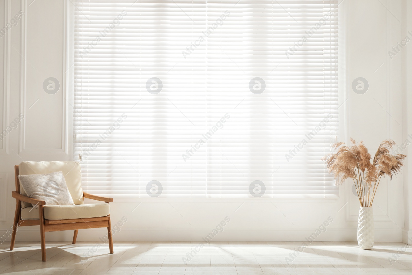 Photo of Cosy armchair and decor near large window with blinds in spacious room. Interior design