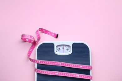 Scales and measuring tape on pink background, top view. Space for text