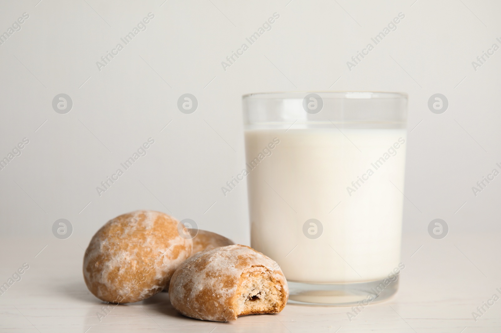 Photo of Tasty homemade gingerbread cookies and glass of milk on white table