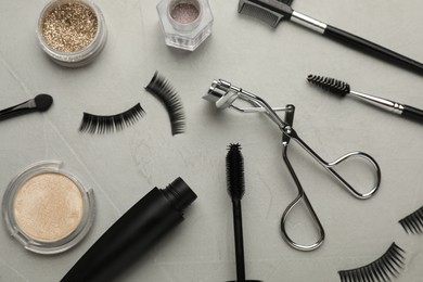 Photo of Flat lay composition with eyelash curler, makeup products and accessories on grey table