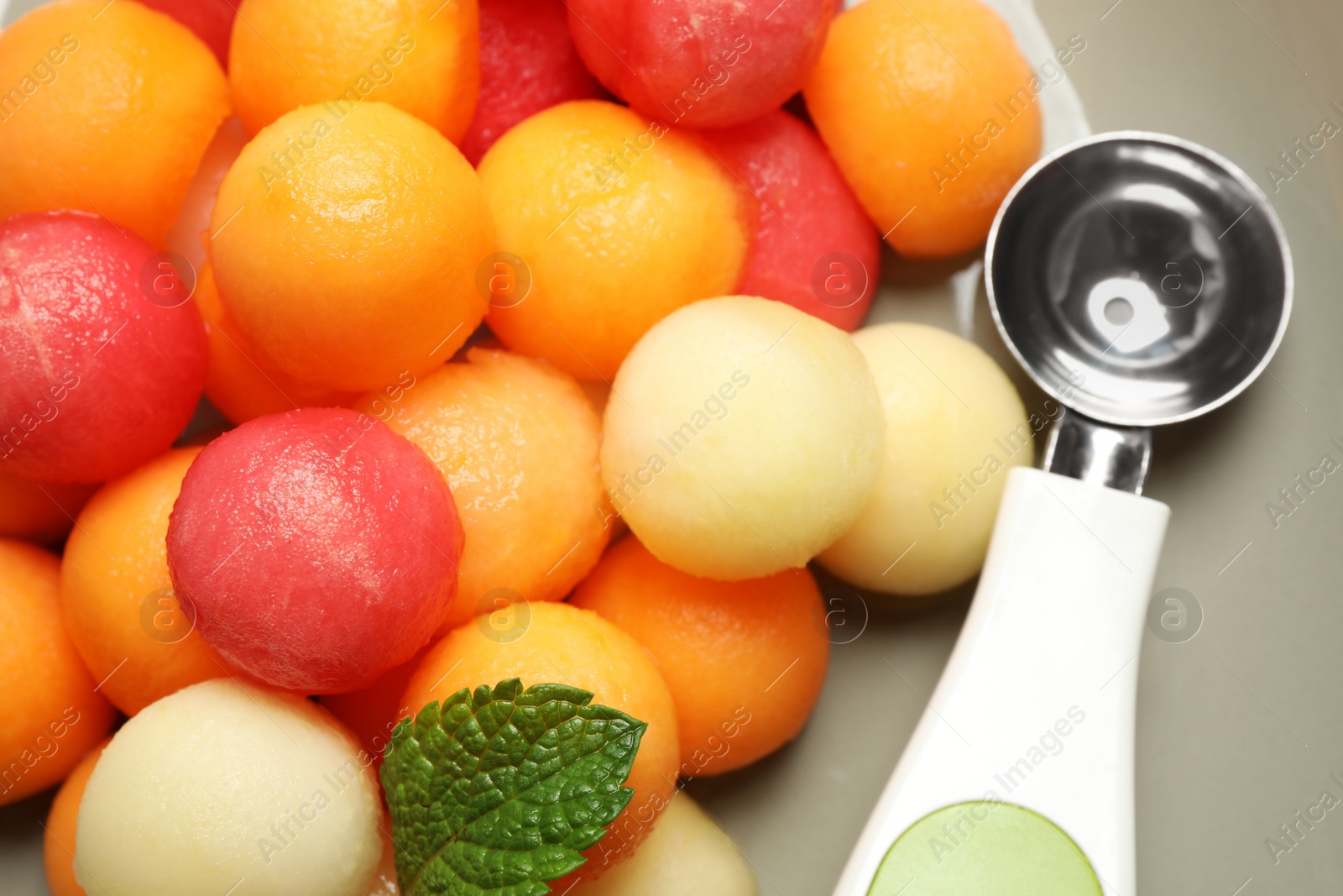 Photo of Melon and watermelon balls with scoop on plate, closeup