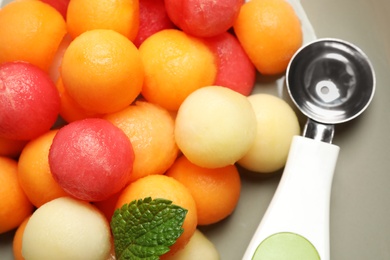 Melon and watermelon balls with scoop on plate, closeup