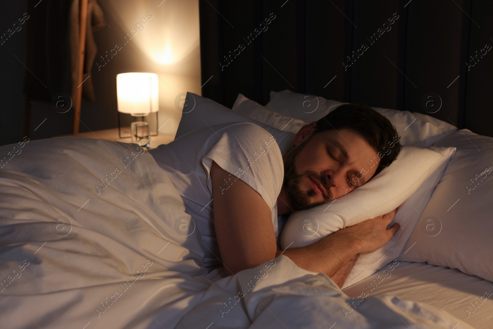 Photo of Handsome man sleeping in bed at night