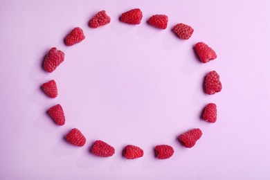 Photo of Frame made of tasty raspberries on lilac background, top view with space for text