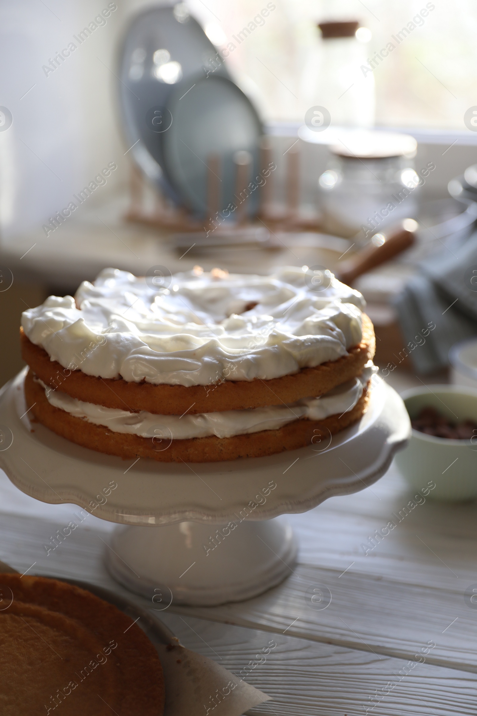 Photo of Delicious homemade layer cake with cream on white wooden table in kitchen
