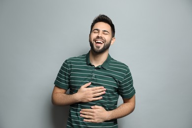 Young man laughing on light grey background. Funny joke