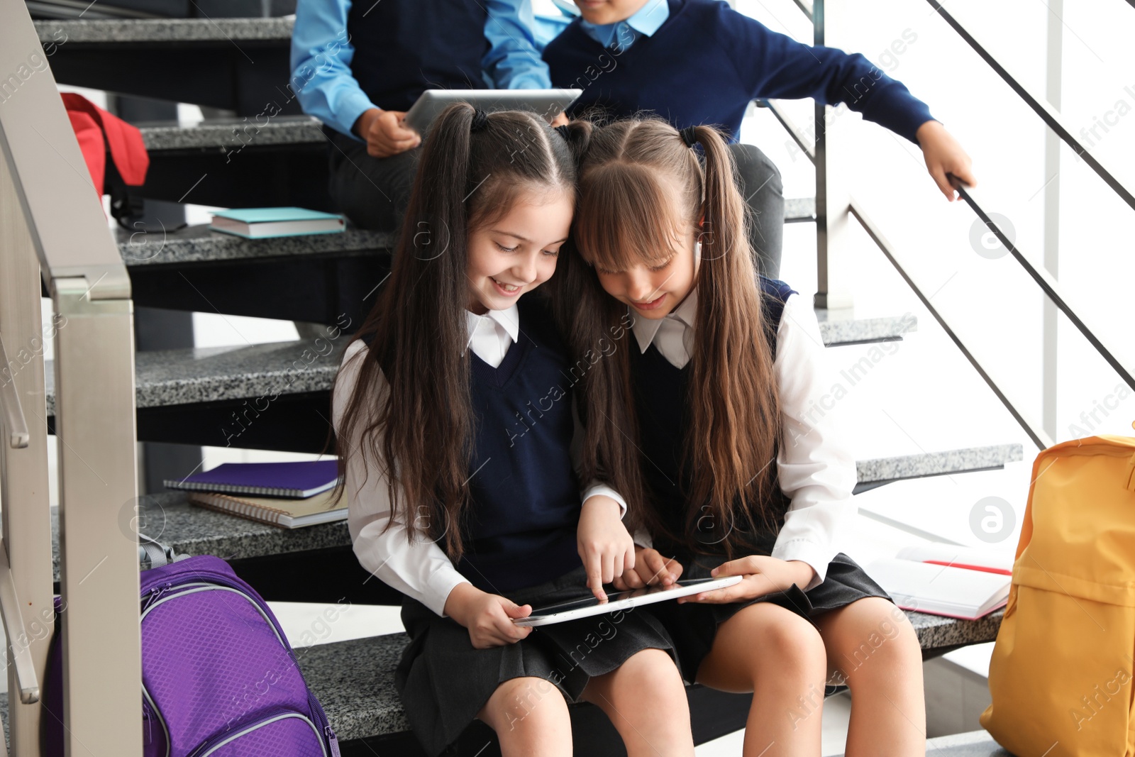 Photo of Little children in stylish school uniform on stairs indoors