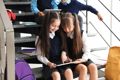 Photo of Little children in stylish school uniform on stairs indoors