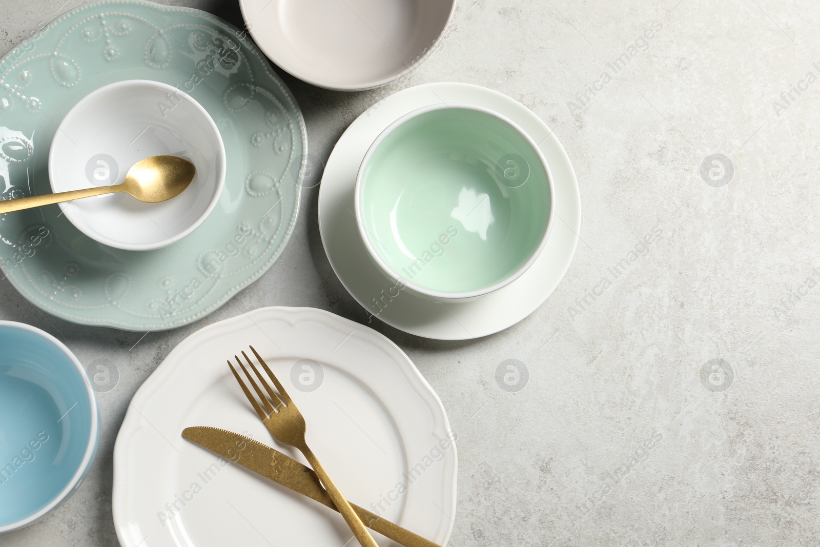 Photo of Beautiful ceramic dishware and cutlery on light grey table, flat lay. Space for text