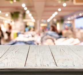 Image of Empty white wooden surface and blurred view of clothes store interior. Space for design