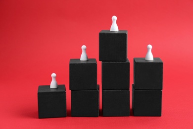 Photo of Black blocks with playing pieces on red background. Roles and responsibility concept