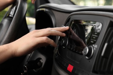 Photo of Choosing favorite radio. Man pressing button on vehicle audio in car, closeup