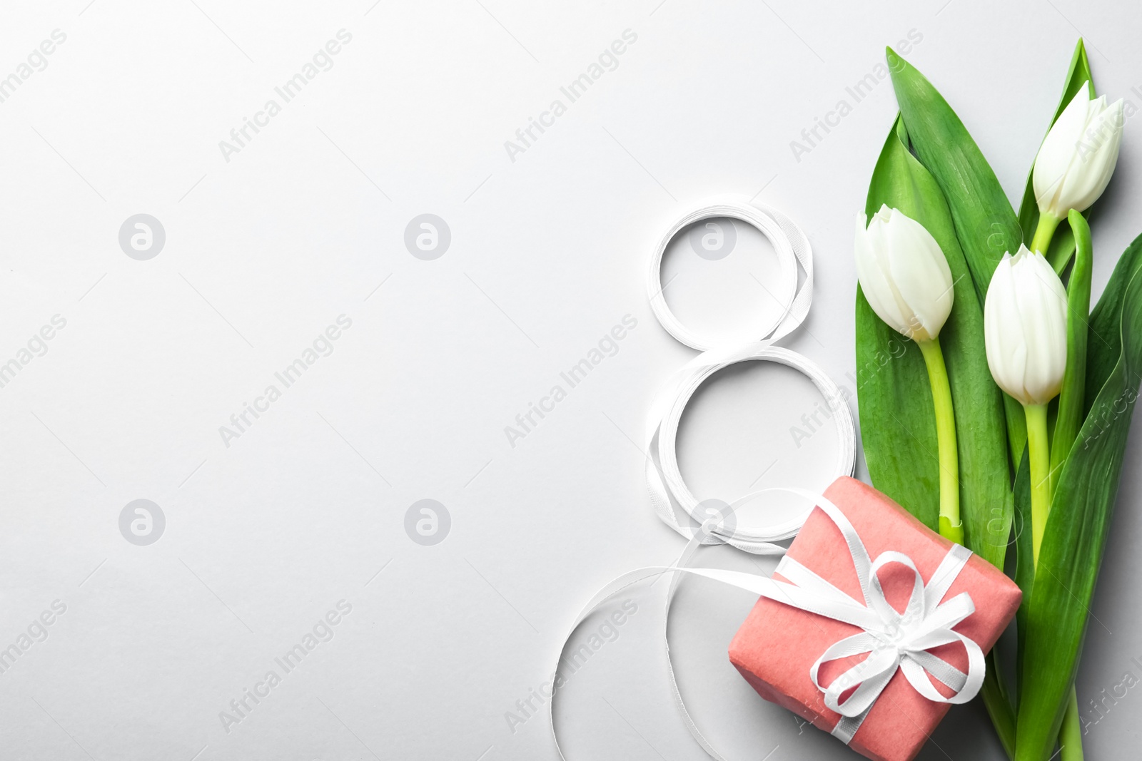 Photo of 8 March card design with tulips, gift and space for text on light grey background, flat lay. International Women's Day