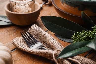Photo of Fork wrapped in burlap on wooden background, closeup. Table setting element