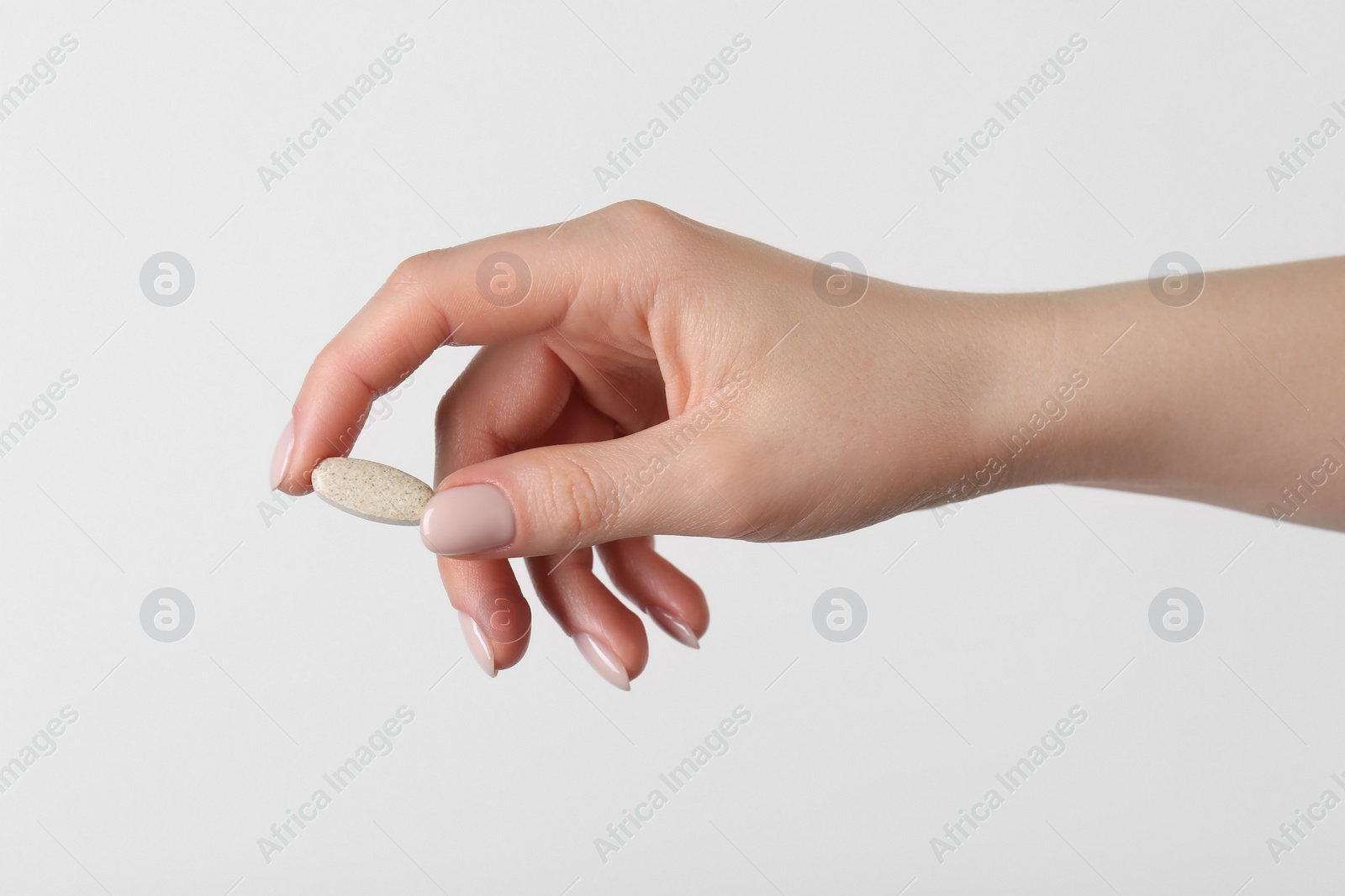 Photo of Woman holding vitamin pill on white background, closeup. Health supplement