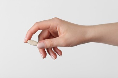 Woman holding vitamin pill on white background, closeup. Health supplement