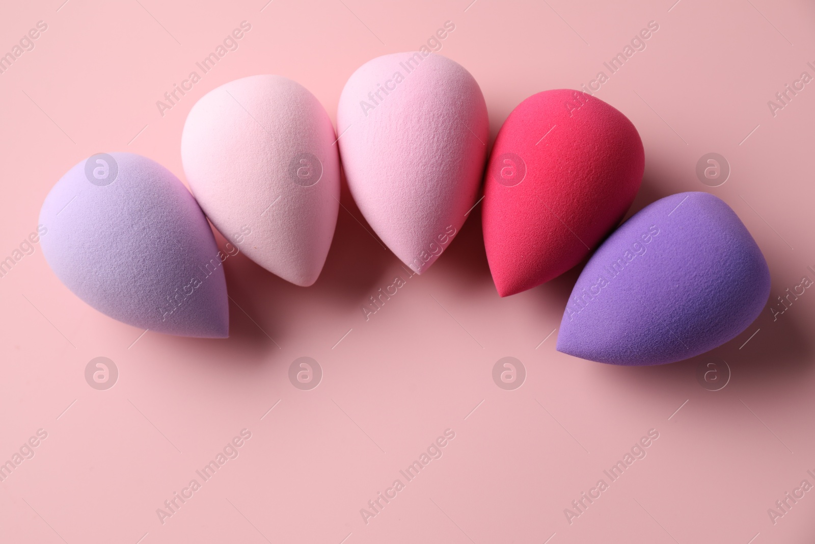 Photo of Many colorful makeup sponges on pink background, flat lay. Space for text