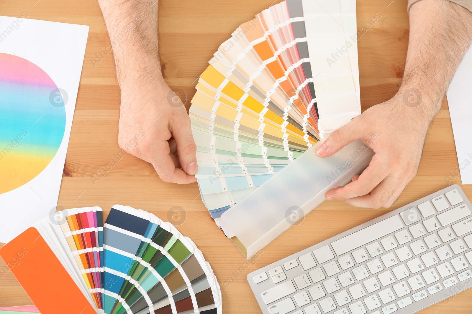 Photo of Designer with paint color palette samples at table, closeup