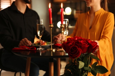 Photo of Couple having romantic dinner in restaurant, focus on bouquet of roses