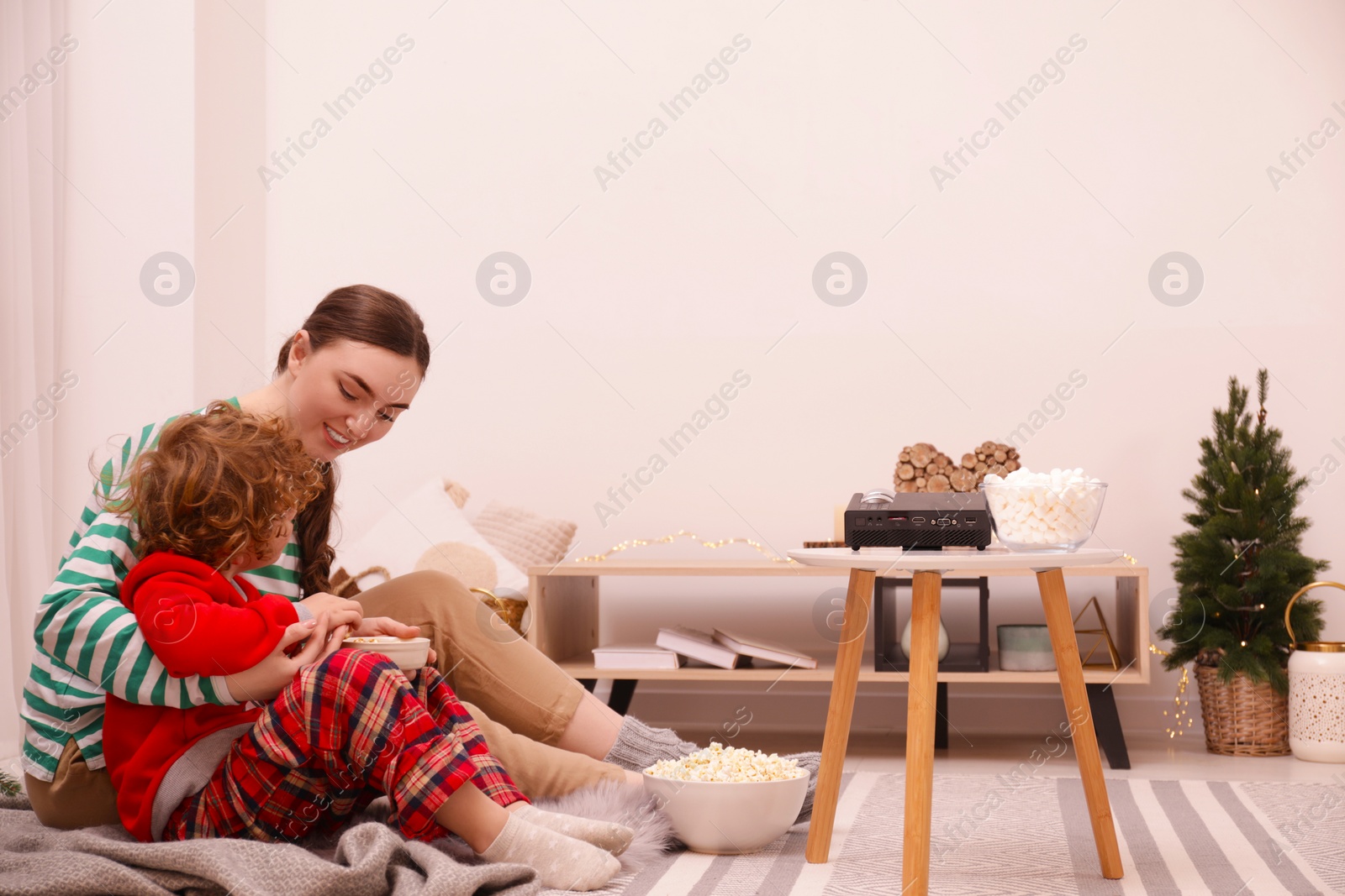 Photo of Mother and son with snacks spending time together at home. Watching movie via video projector