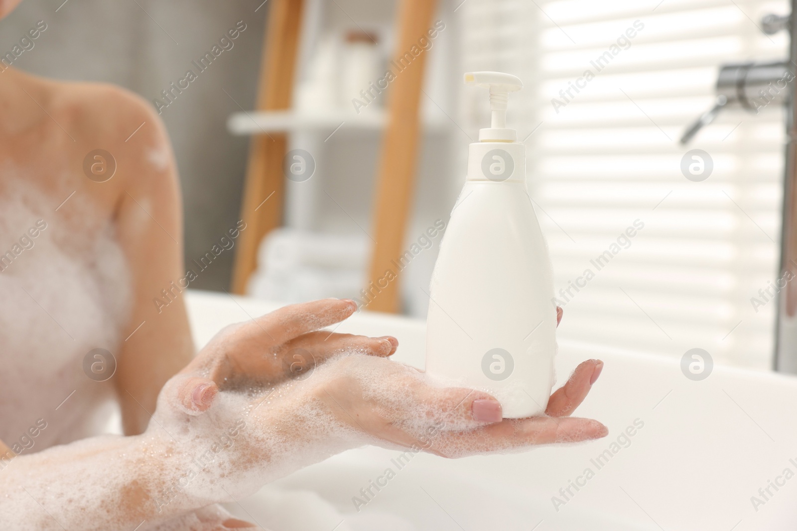 Photo of Woman taking bath with shower gel in bathroom, closeup